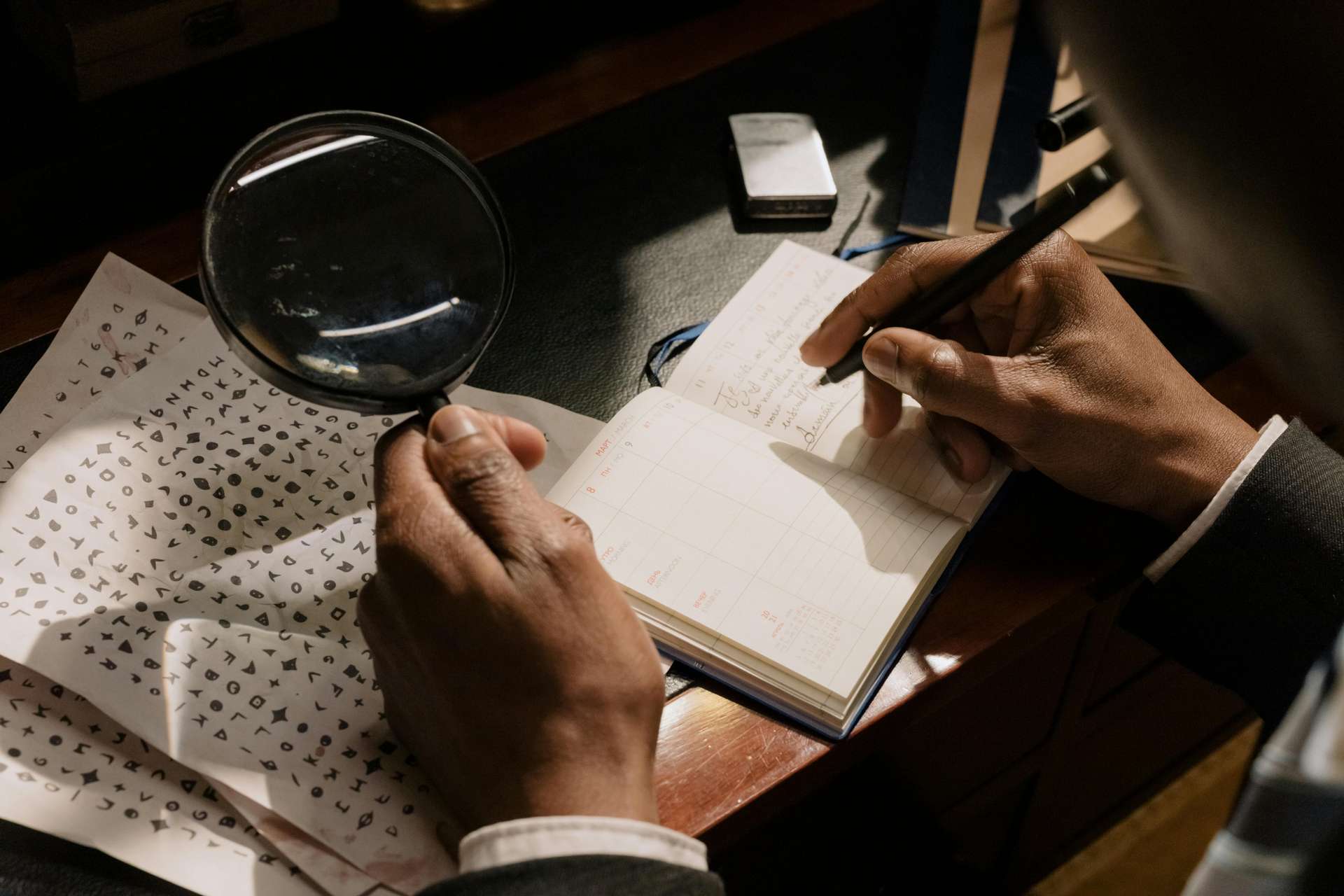 a man holding a magnifying glass over encrypted text on paper and writing in a notebook