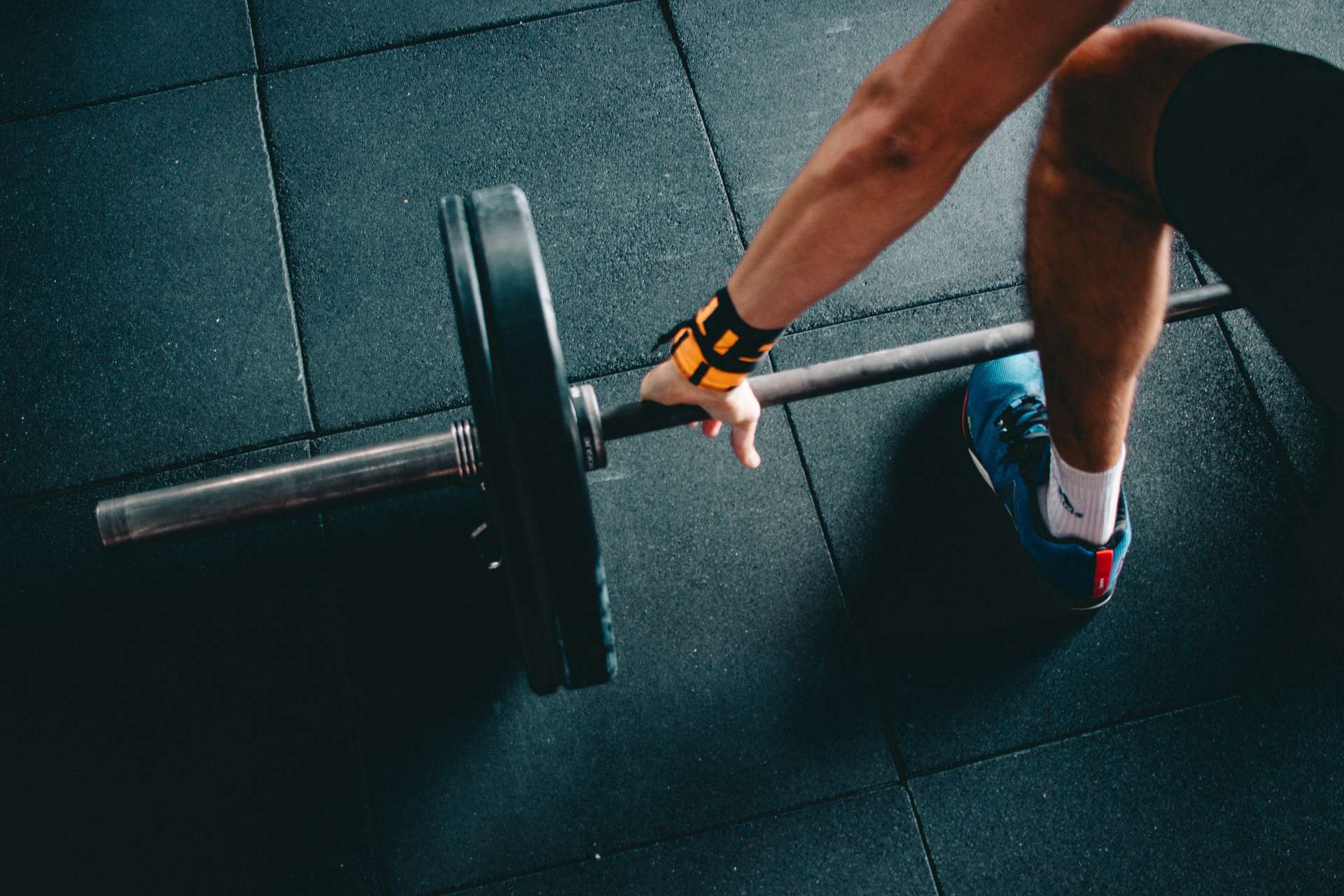 a barbell on the floor with an arm getting ready to lift