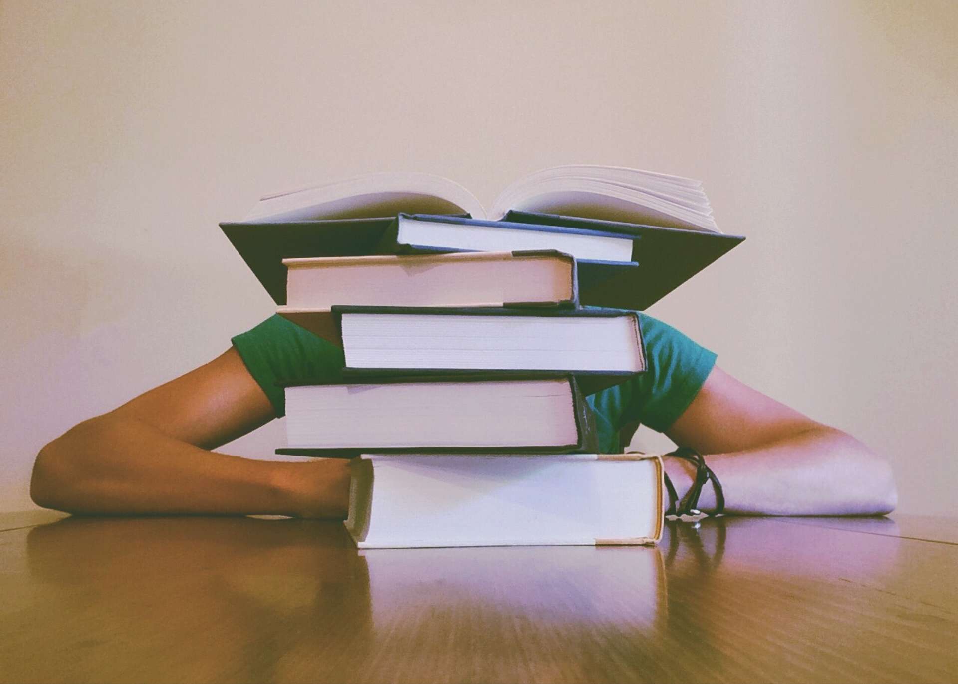 A stack of books with a person hidden behind them