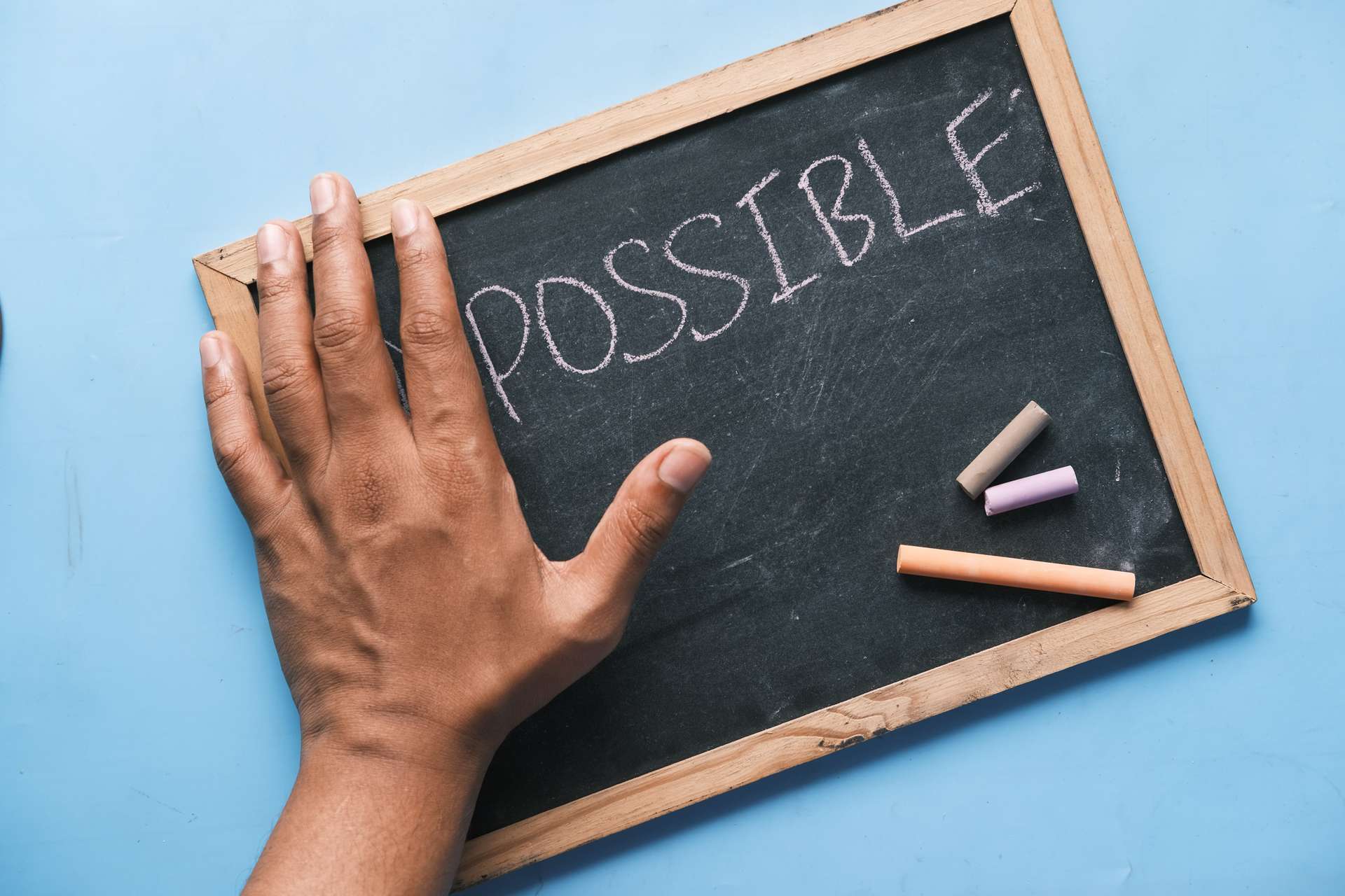 impossible written on a chalk board covered by hand to make it read possible